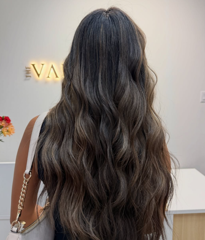 The Vault Aesthetics & Beauty Co. salon interior with styled hair and illuminated sign